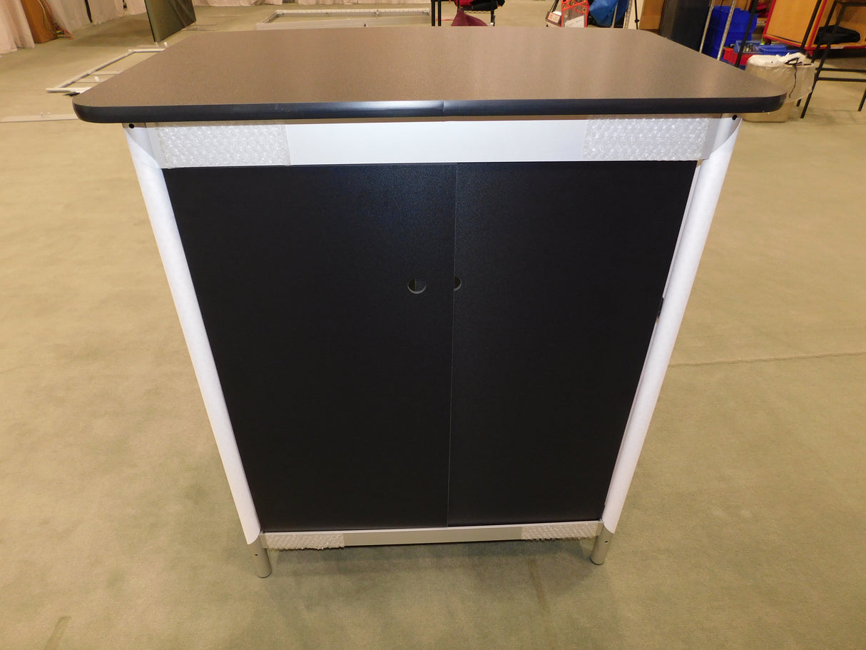 Black and white cabinet with a flat top on a concrete floor.