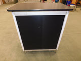 Black and white cabinet with a flat top on a concrete floor.